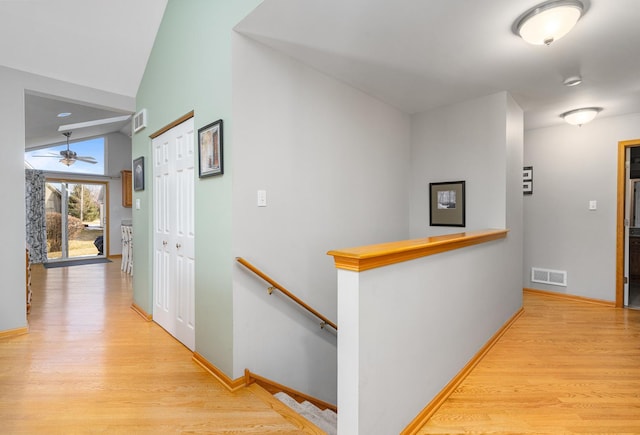 hall with lofted ceiling and light wood-type flooring