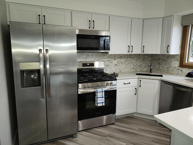 kitchen featuring stainless steel appliances, sink, white cabinets, and light wood-type flooring