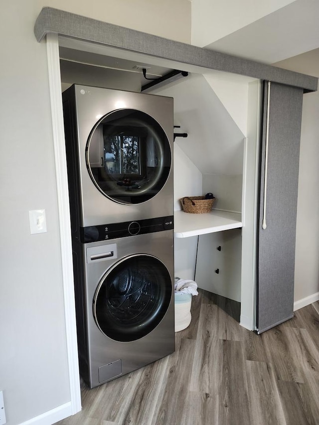 laundry area with stacked washer / drying machine and wood-type flooring