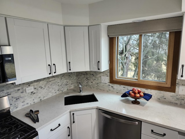 kitchen with sink, stainless steel appliances, white cabinets, and light stone countertops