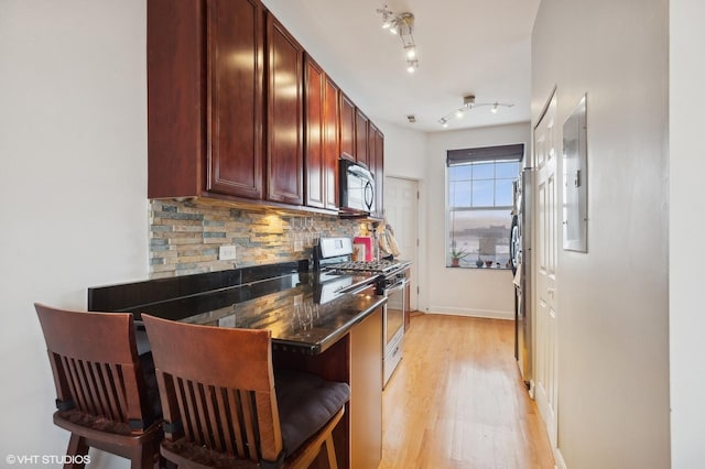 kitchen with a kitchen bar, light hardwood / wood-style floors, gas stove, and decorative backsplash