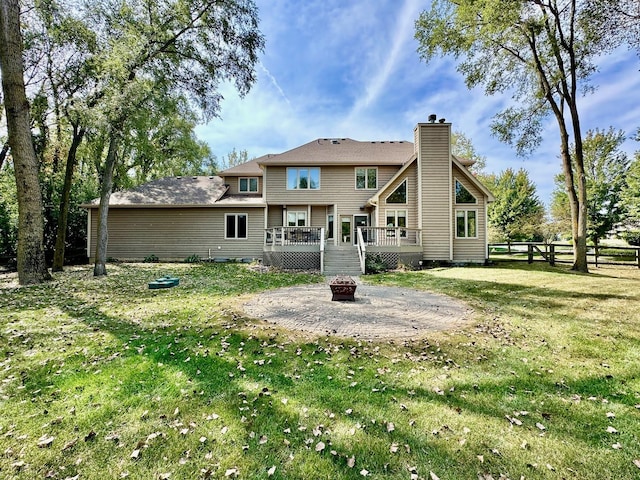 rear view of property with a patio area, a deck, an outdoor fire pit, and a yard