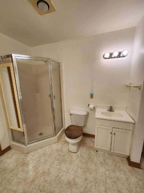 full bathroom with a stall shower, baseboards, toilet, tile patterned floors, and vanity