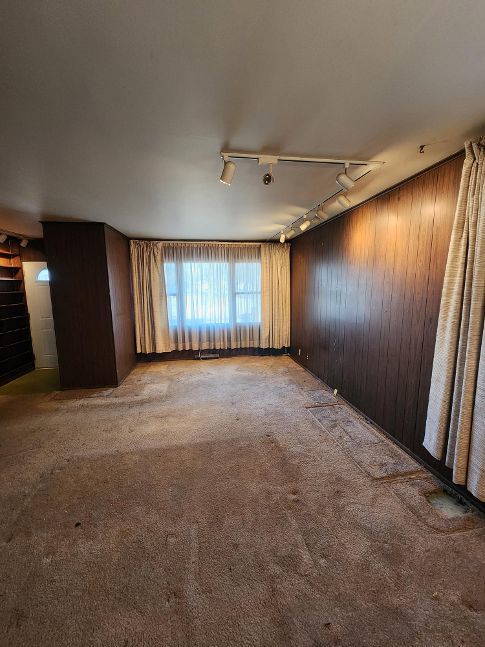 carpeted spare room with wood walls