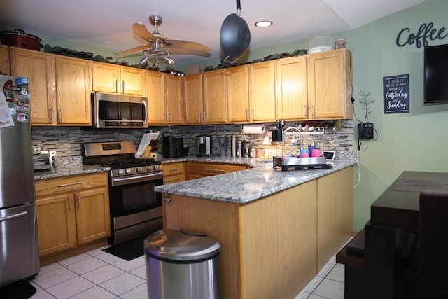 kitchen featuring ceiling fan, appliances with stainless steel finishes, backsplash, light stone countertops, and light tile patterned flooring