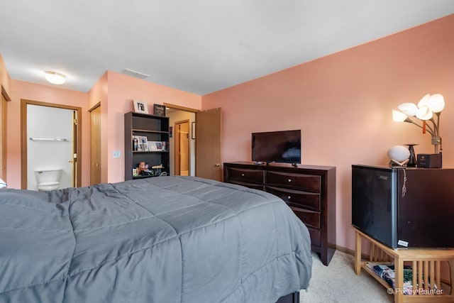 bedroom with ensuite bathroom and light colored carpet