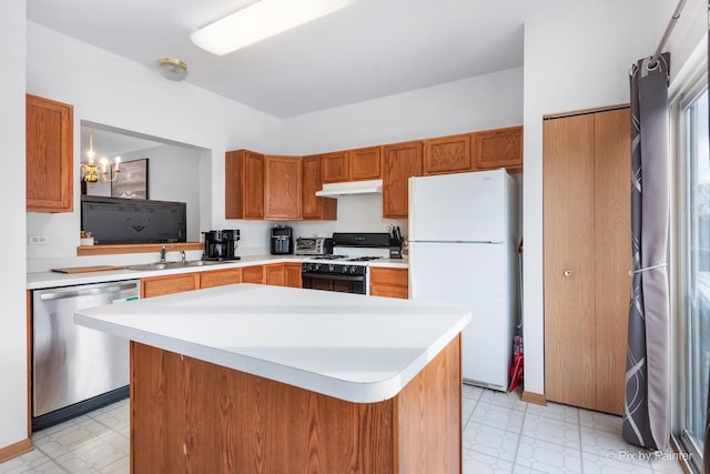 kitchen with white appliances, a kitchen island, a notable chandelier, and sink