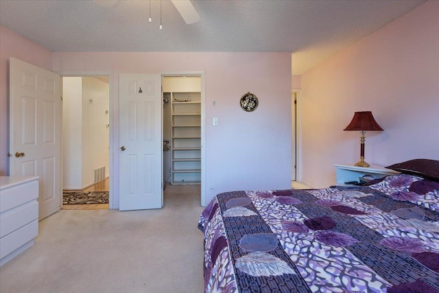 bedroom featuring ceiling fan, a textured ceiling, a closet, and a walk in closet