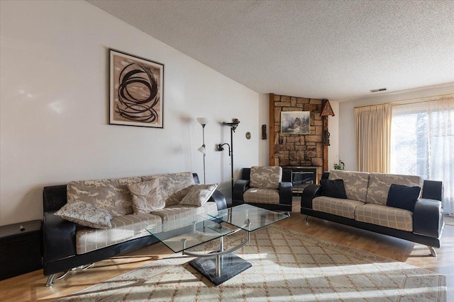 living room with lofted ceiling, a fireplace, a textured ceiling, and wood-type flooring