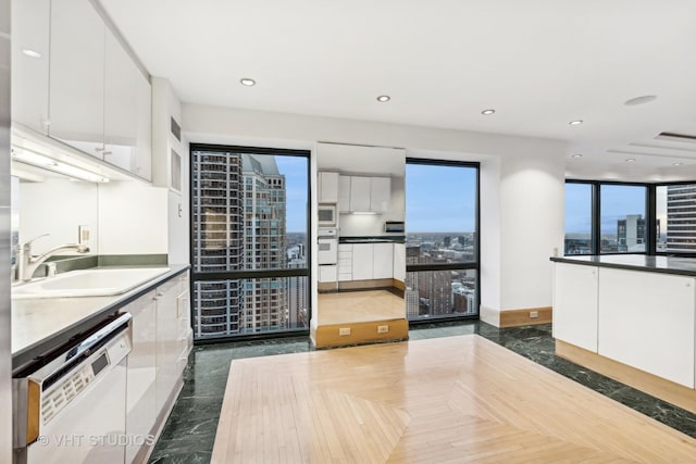 kitchen with white cabinets, white appliances, dark parquet floors, and sink