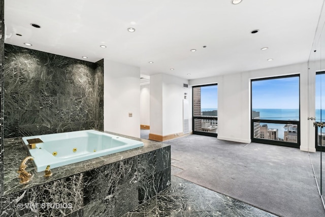 bathroom featuring tiled tub and a water view