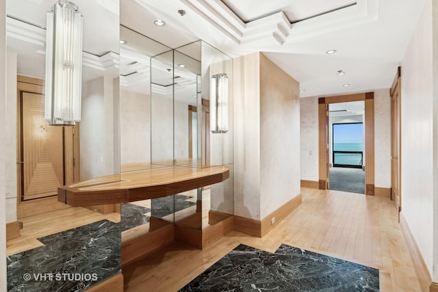 interior space with light hardwood / wood-style floors, ornamental molding, and a tray ceiling