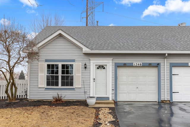 view of front of property with a garage, a shingled roof, fence, and aphalt driveway