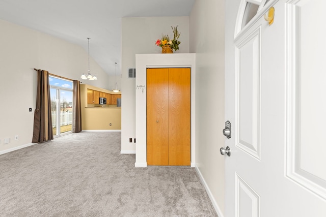 foyer entrance with a notable chandelier, visible vents, light carpet, high vaulted ceiling, and baseboards