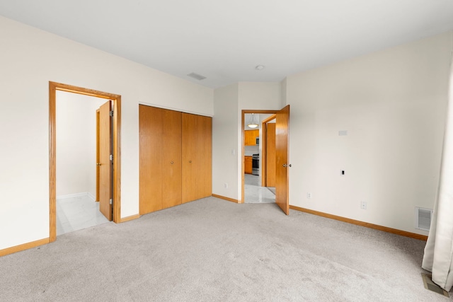 unfurnished bedroom with light colored carpet, a closet, visible vents, and baseboards