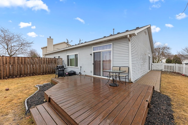 deck with a yard, a fenced backyard, and a grill