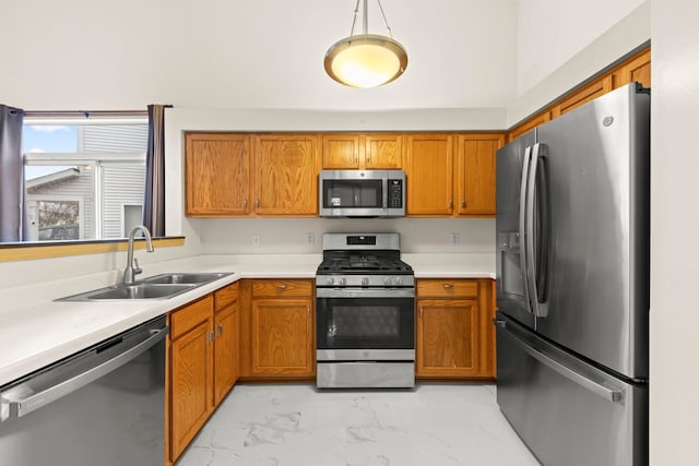 kitchen with appliances with stainless steel finishes, brown cabinets, marble finish floor, light countertops, and a sink