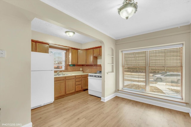 kitchen with sink, stove, light hardwood / wood-style floors, a textured ceiling, and white fridge