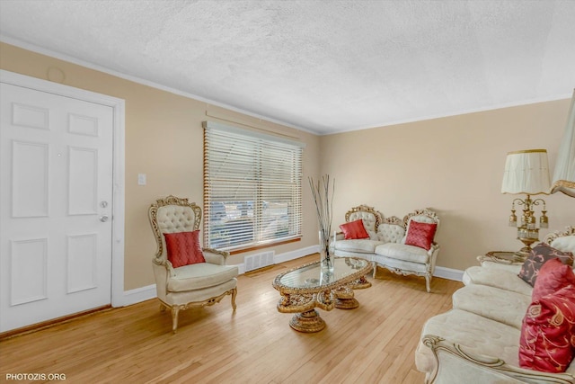 living room with hardwood / wood-style flooring, ornamental molding, and a textured ceiling