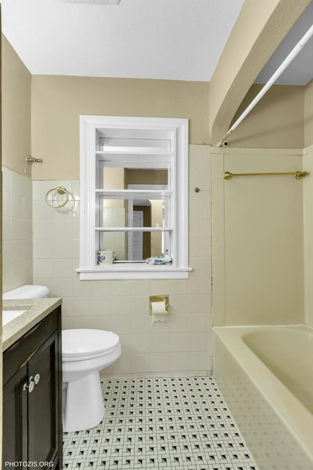 bathroom with tile patterned flooring, vanity, tile walls, and toilet