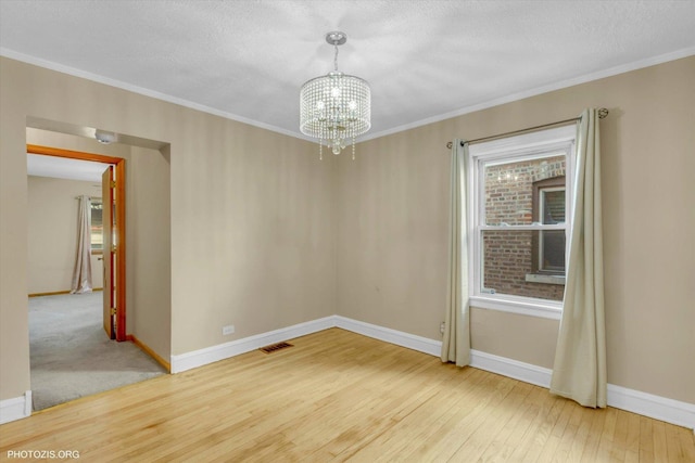 unfurnished room featuring an inviting chandelier, crown molding, wood-type flooring, and a textured ceiling