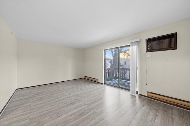 spare room with baseboard heating, light hardwood / wood-style flooring, and a wall mounted AC