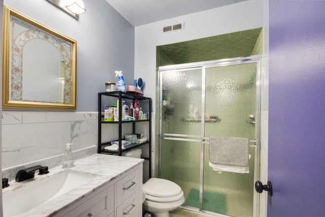 bathroom with toilet, a shower with shower door, and vanity