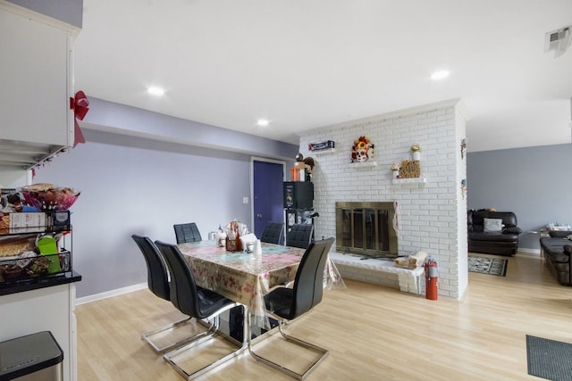 dining area with a brick fireplace and light hardwood / wood-style floors