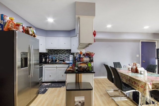 kitchen featuring tasteful backsplash, sink, white cabinetry, light wood-type flooring, and stainless steel fridge