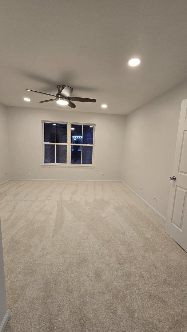 carpeted spare room with ceiling fan