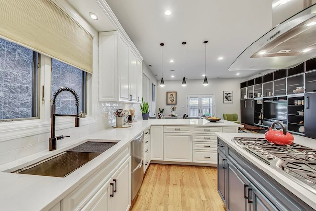 kitchen with white cabinets, sink, hanging light fixtures, kitchen peninsula, and stainless steel appliances