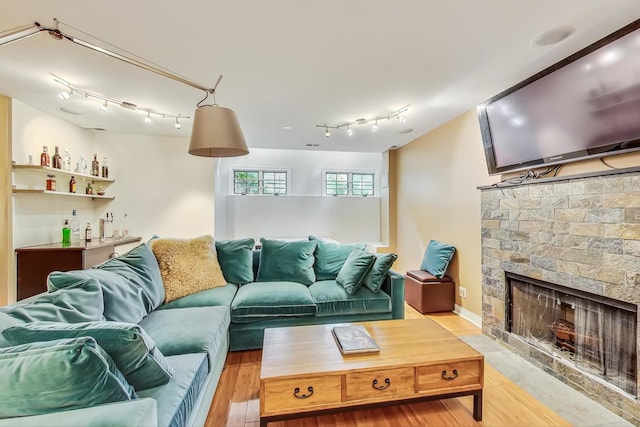 living room featuring a stone fireplace and bar area