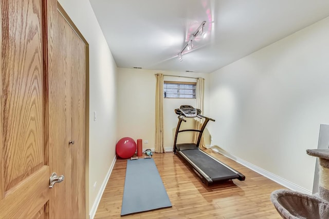 workout room featuring light wood-type flooring and rail lighting