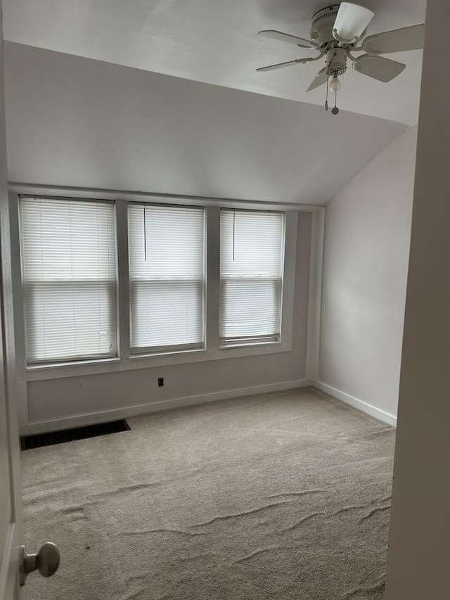 empty room with lofted ceiling, ceiling fan, carpet, and plenty of natural light