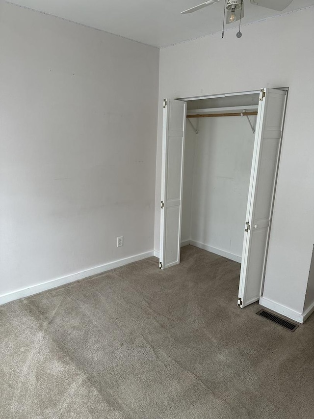 unfurnished bedroom with ceiling fan and dark colored carpet