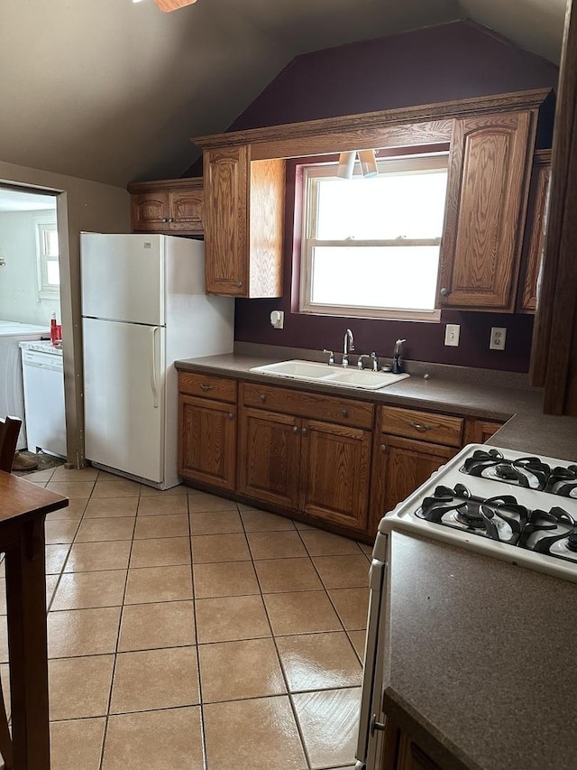 kitchen with lofted ceiling, sink, light tile patterned flooring, and white appliances