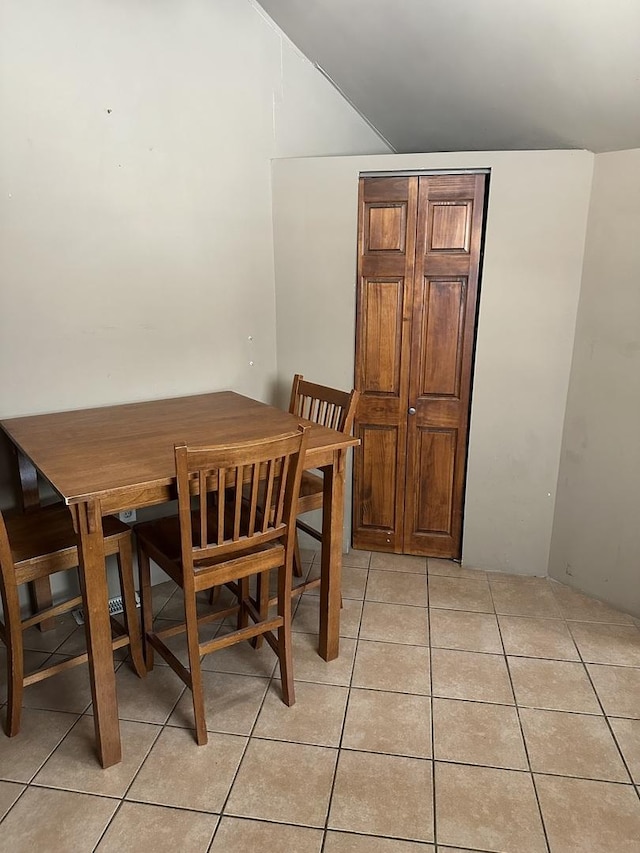 dining room with light tile patterned floors and vaulted ceiling