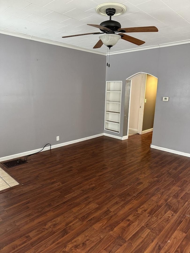 empty room featuring ceiling fan, ornamental molding, dark hardwood / wood-style floors, and built in shelves