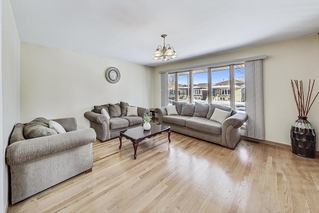 living room featuring light wood-type flooring and a notable chandelier