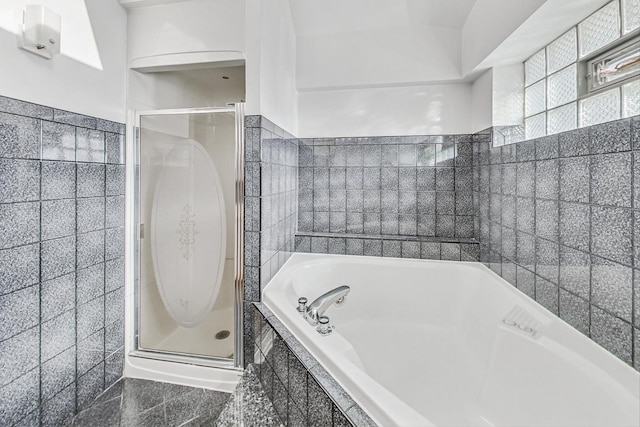 bathroom with tile walls and shower with separate bathtub