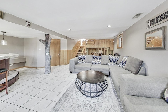 living room featuring wood walls and light tile patterned floors