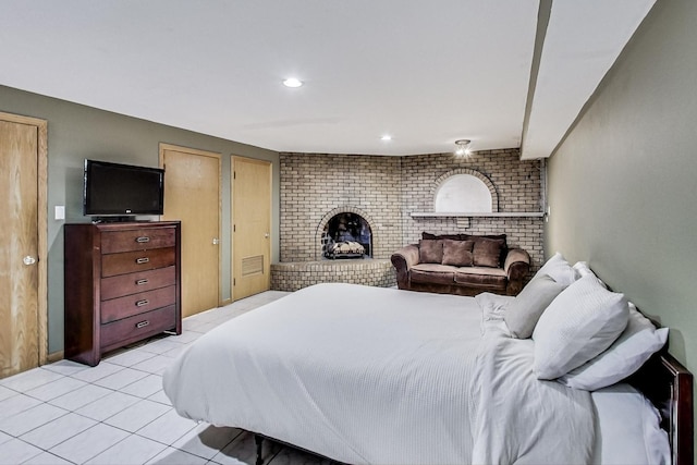 tiled bedroom featuring a brick fireplace and multiple closets