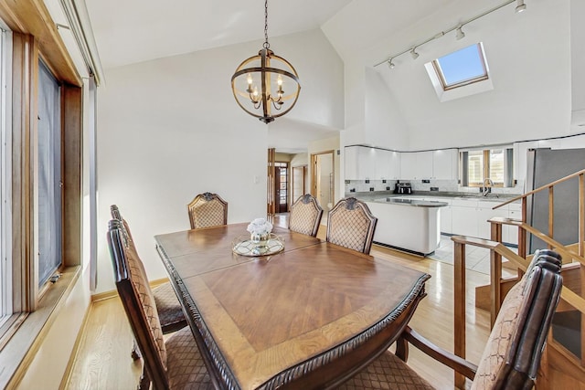 dining area featuring sink, a chandelier, a skylight, and light hardwood / wood-style floors