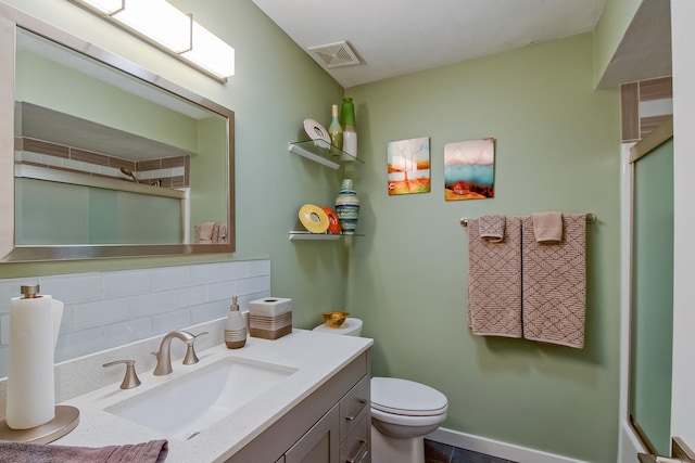 bathroom featuring vanity, backsplash, toilet, and walk in shower