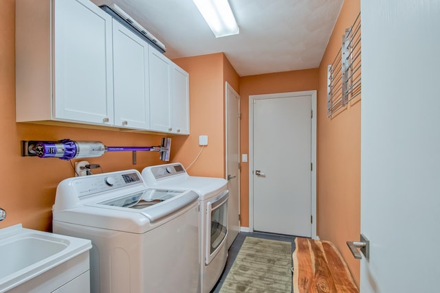 clothes washing area featuring cabinets, washing machine and dryer, and sink