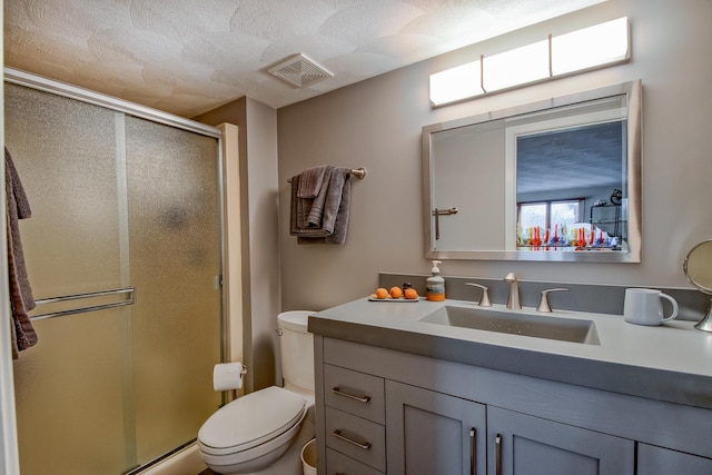 bathroom featuring a shower with door, vanity, a textured ceiling, and toilet