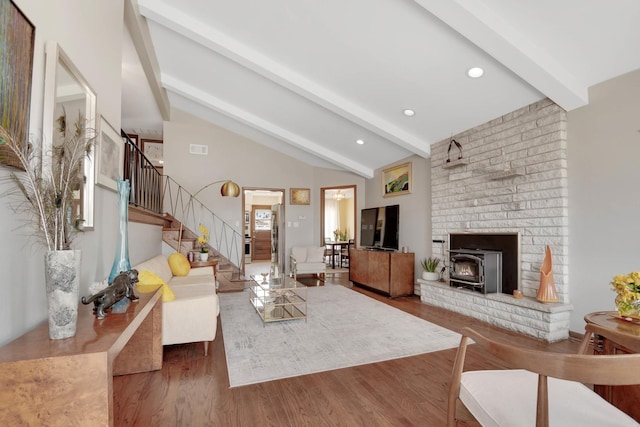 living room featuring vaulted ceiling with beams, dark wood-type flooring, and a wood stove