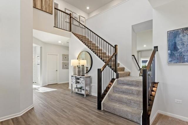 stairs featuring hardwood / wood-style floors and a high ceiling