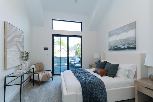 carpeted bedroom featuring access to exterior and a high ceiling