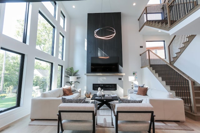 living room with a towering ceiling, a healthy amount of sunlight, and light hardwood / wood-style floors